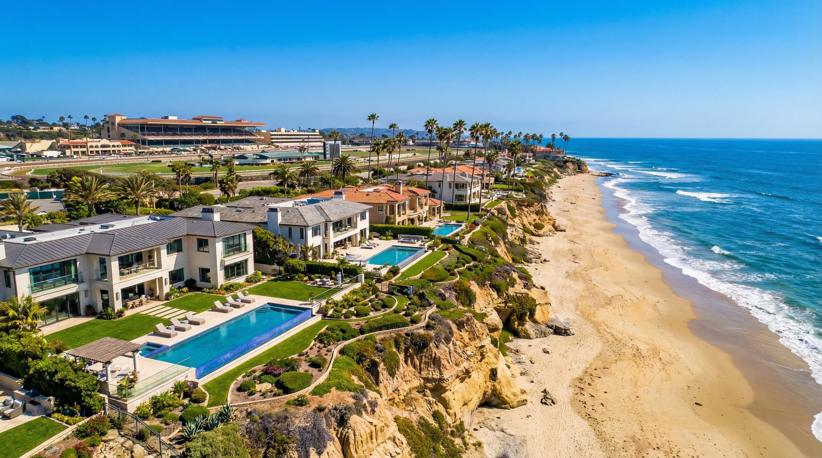 Exclusive Del Mar California coastal village with luxury homes on bluffs overlooking ocean, Del Mar Racetrack area visible, and pristine beaches