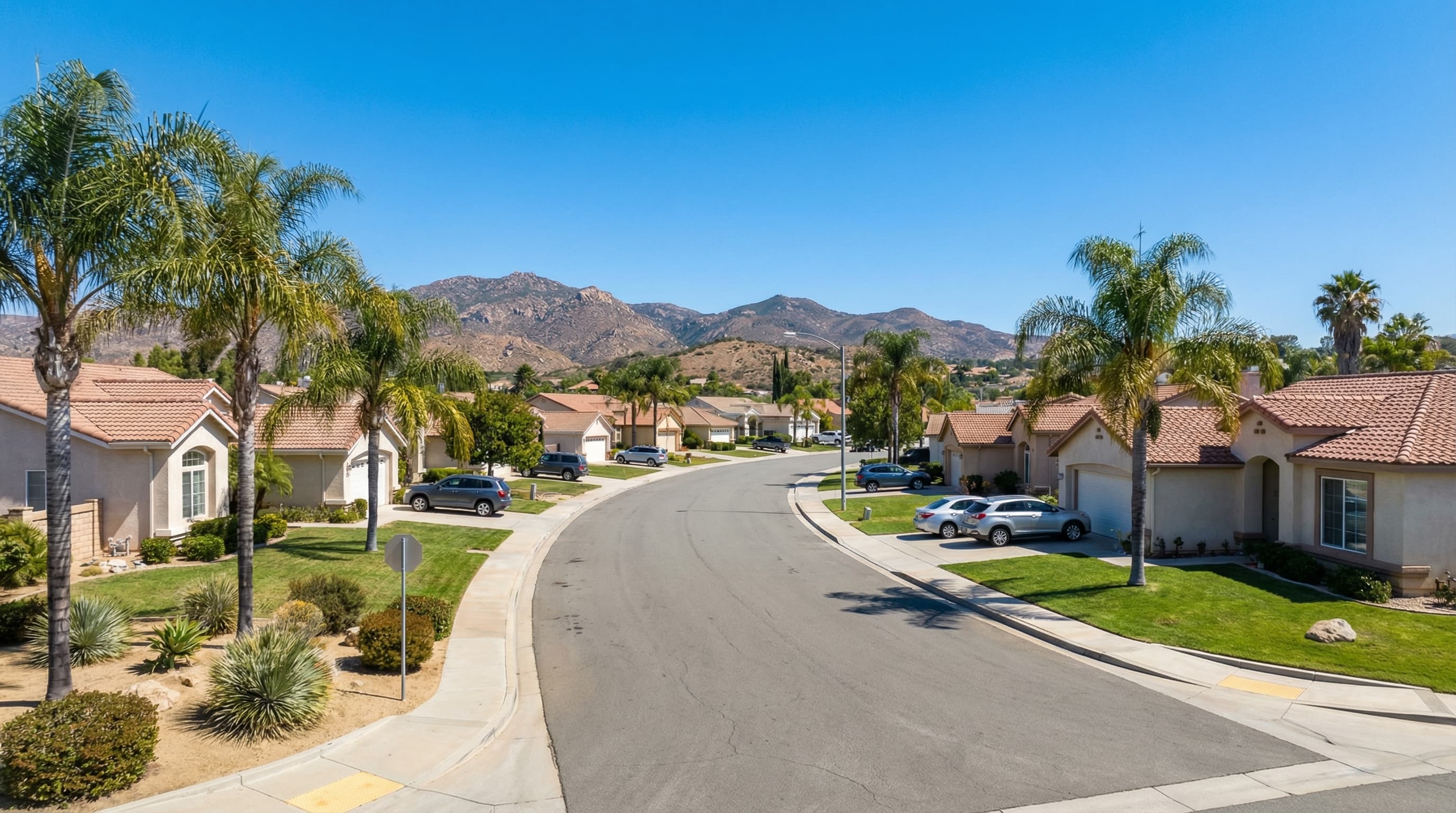 Family-friendly El Cajon California valley community with single family homes, mountain backdrop, palm trees and mature landscaping on a bright sunny day