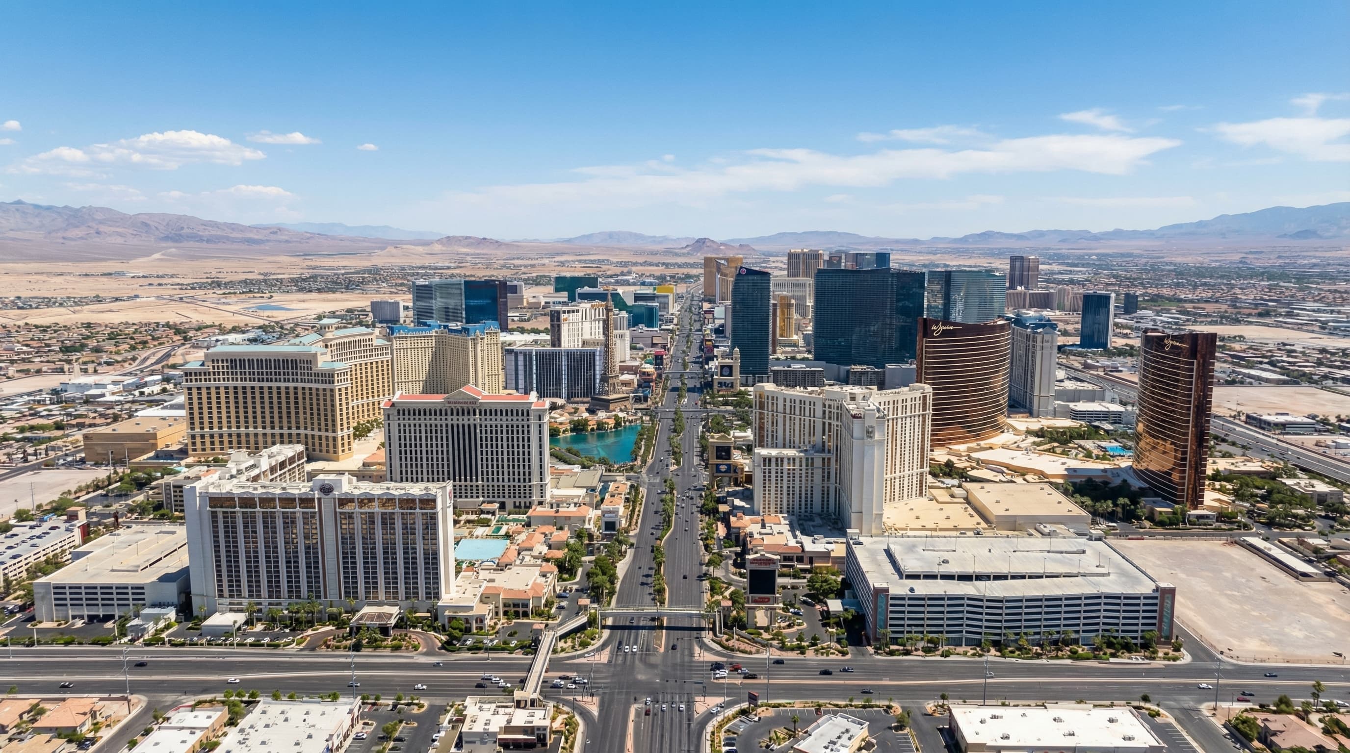 Aerial view of Las Vegas Nevada skyline at twilight with illuminated Strip, desert mountains, and sprawling master-planned communities