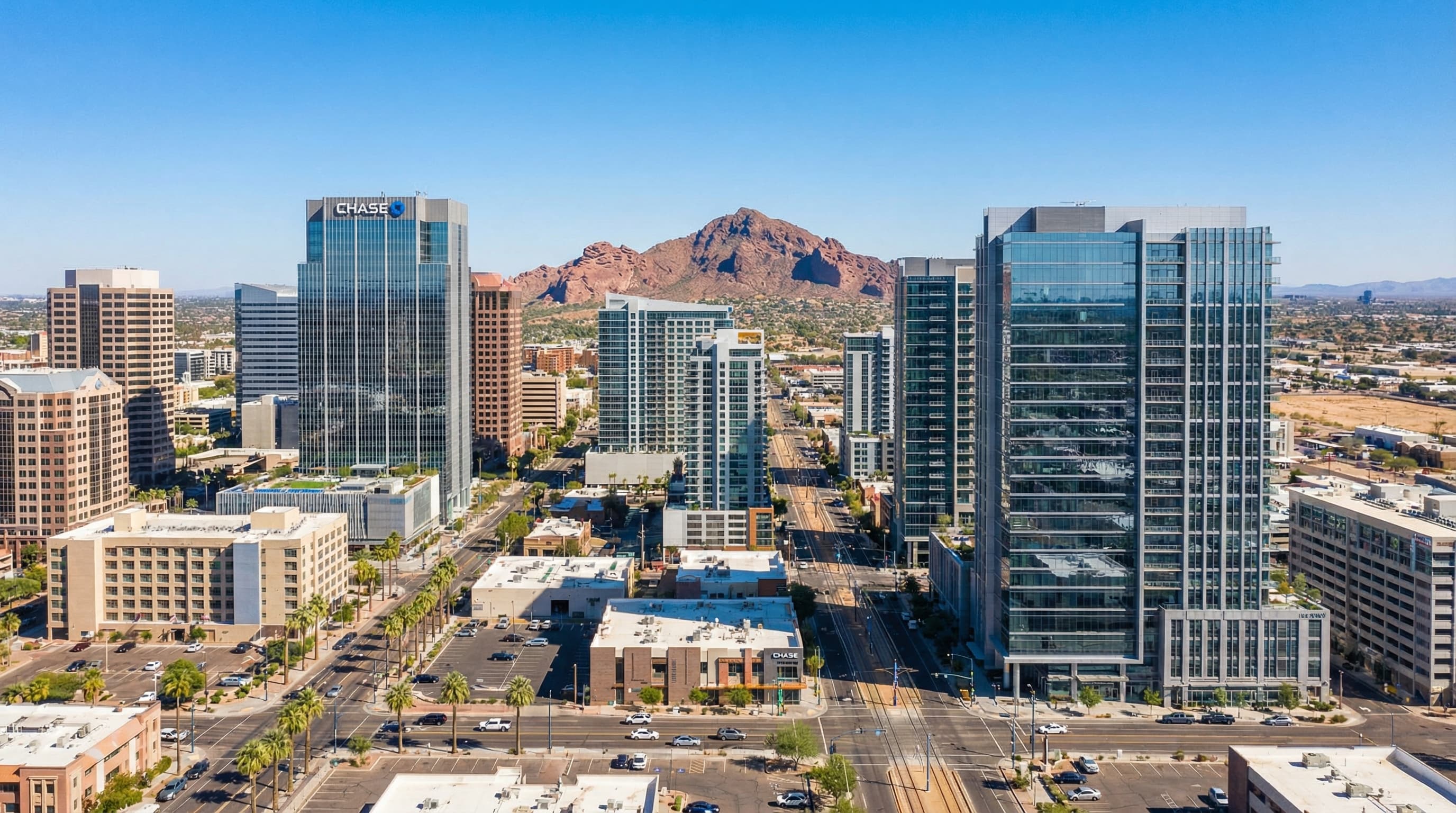 Modern downtown Phoenix Arizona skyline with palm trees and Camelback Mountain backdrop