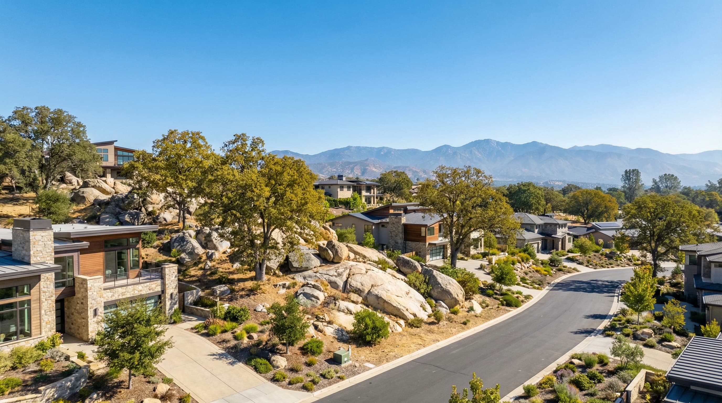Upscale Rocklin California foothill community with modern homes, granite outcroppings, oak trees, and Sierra Nevada mountain views on a bright sunny day
