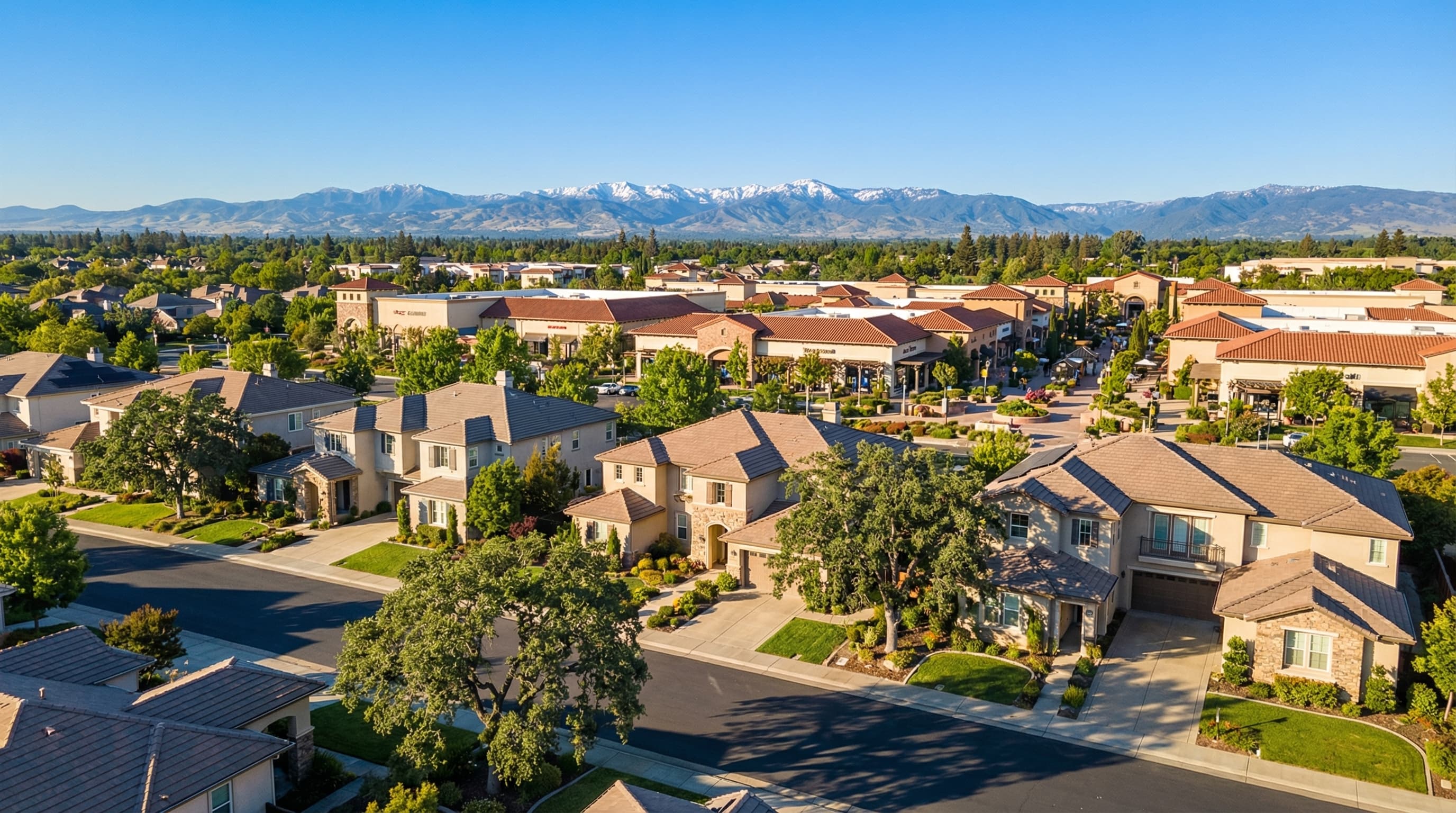 Thriving Roseville California suburban community with upscale homes, shopping centers, mature oak trees, and Sierra Nevada mountain views in the distance